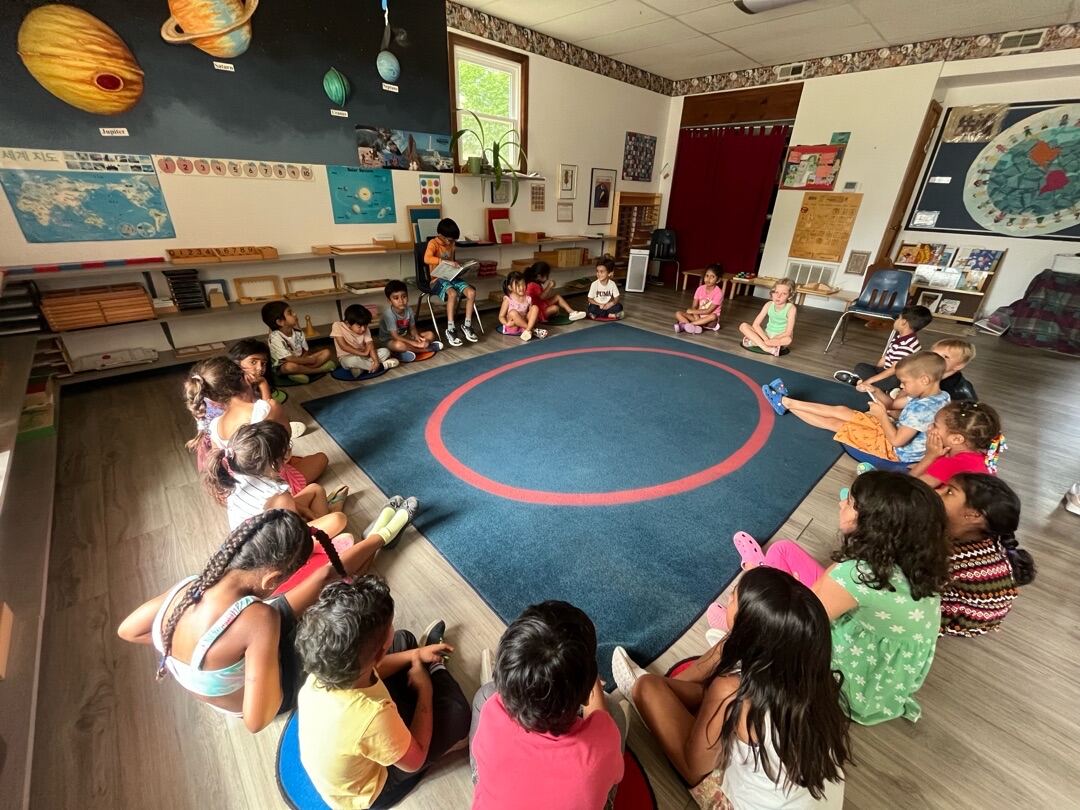 Children sitting together in a circle in the Montessori classroom