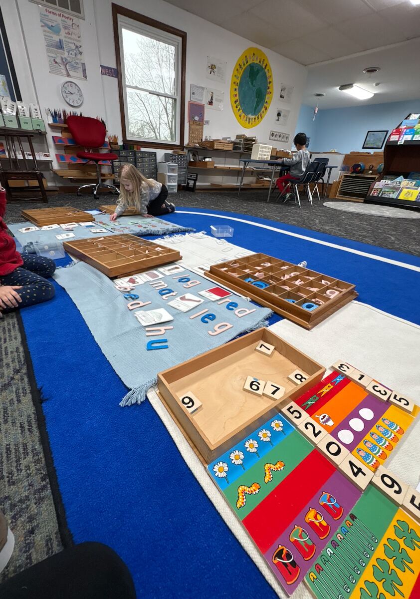 Montessori math and sensorial materials laid out on a classroom rug