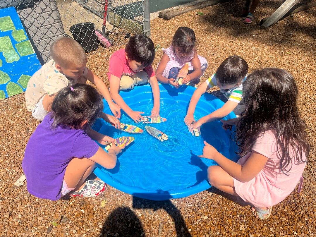 Children playing together around a water table outdoors